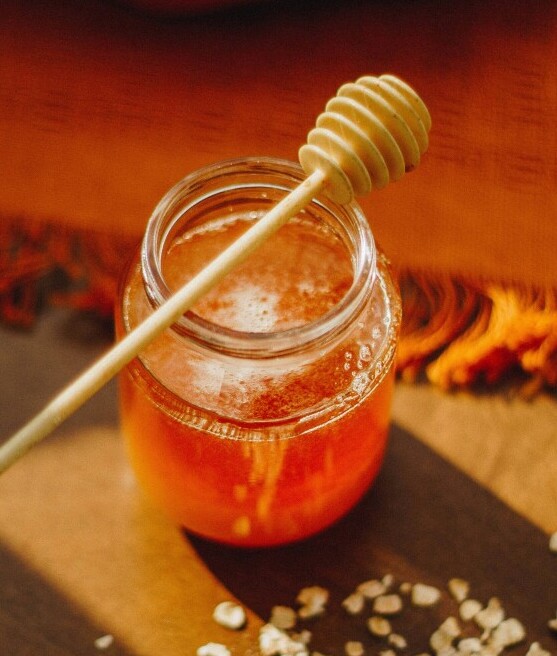 A jar of honey with foam on the surface