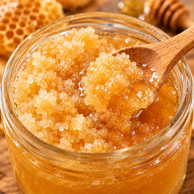 Close-up of natural honey crystallisation showing grainy glucose crystals inside a jar.