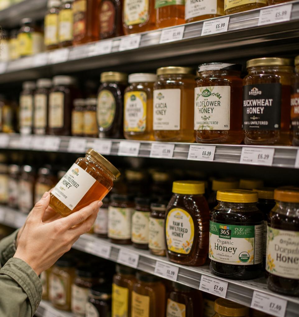 Consumer reading honey labels while shopping for honey in a supermarket.
